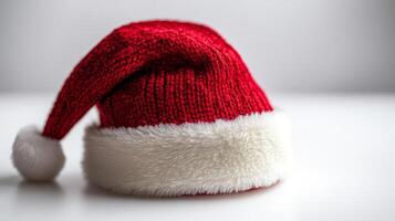 A cozy red Santa hat resting on a white surface, symbolizing the joy and warmth of the holiday season during festive celebrations photo