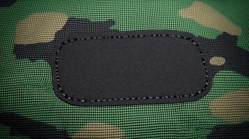The texture of a camouflage fabric features a blank patch waiting for personalization or labeling photo