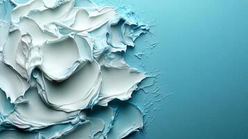 Delicate layers of white cream swirl together, creating a petal-like form on a serene blue canvas photo