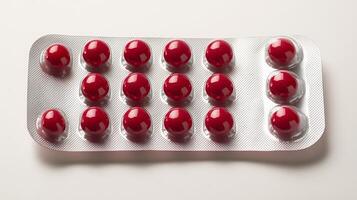 Red capsules are arranged neatly in a shiny silver pack on a clean white background photo