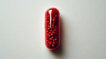 A bold red capsule sits on a flat surface, filled with tiny, colorful spheres photo