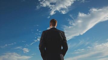 Ambitious businessman with determination and vision in the corporate world, looking at the sky photo