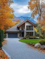 This beautiful house has a landscaped front yard and a gravel driveway, adding charm with autumn colors and a mountain backdrop, creating an inviting atmosphere in a peaceful neighborhood photo