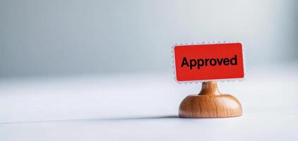 Approved stamp on wooden base signifies acceptance and validation, perfect for documents and forms. This conveys sense of completion and assurance photo