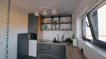 Modern compact kitchen with open shelves - A small modern kitchen featuring sleek cabinetry, open shelves with decor, and a bright window offering natural light and a stylish minimalist design. video