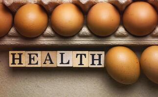 Health word wood block put in paper tray beside blurred Eggs with brown shell photo