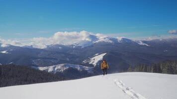A man with a backpack travels in the mountains in winter. He is happy and smiles in nature. The concept of travel and active lifestyle. 4K video