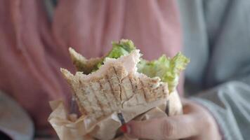 A Healthy and Nutritious Sandwich with Fresh Lettuce in Hand on a Dining Table video