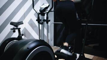 woman running on a treadmill, elliptical trainer in health club. A fit girl dressed in sports outfit, doing cardio cross training on a cross-trainer. Doing warm-up before training session video