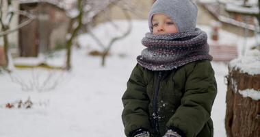 Child building snowball in snowy backyard video