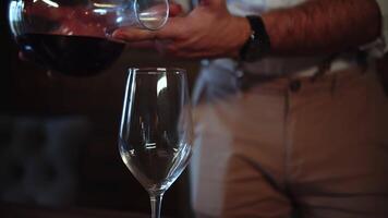 Man pouring red wine into a glass from decanter video