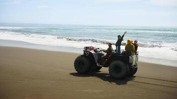 Group Of Happy Travelers Riding On Monster Quad On Ocean Beach, Exploring Unknown Terrains video