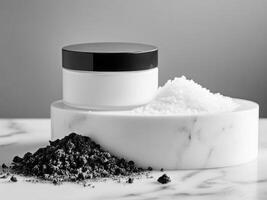 White cosmetic scrub jar on white podium with coal dust and salt crystals on marble table. Black and white colors. Minimalistic photo style.