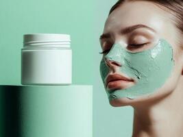 White cosmetic jar standing on podium and woman's face in green clay mask. Pastel green background. Minimalistic photo style.