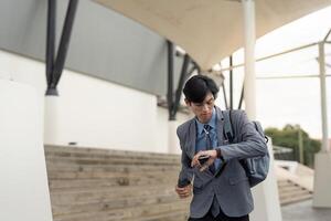 Asian businessman checking watch outside modern office photo