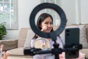 Asian woman smiling while using blush in home makeup routine photo