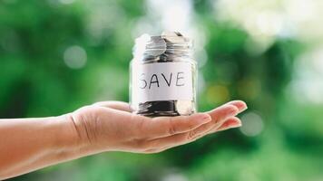 A hand holding a jar of coins with the word save written on it. saving money concept. photo