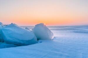 Winter landscape. A frozen surface of ice with snow intersected by many cracks. photo