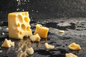 A Block of Swiss Cheese Breaking Apart on a Dark Surface photo