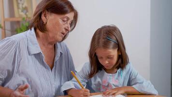 Grandmother sitting with girl drawing in book at home video