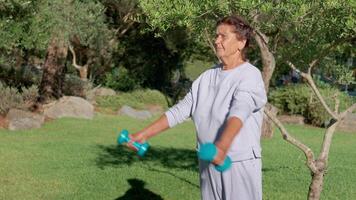 Senior Woman Exercises With Dumbbells in a Sunny Park Setting During Morning Hours video