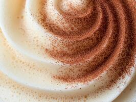 Close up of a frothy coffee drink with cocoa powder swirls photo