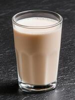 Creamy milkshake in glass on dark background photo
