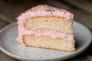 Delicious layered cake with pink frosting and colorful sprinkles photo