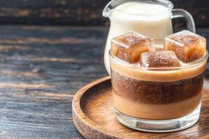 Creamy cold brew coffee with ice cubes and caramel candy photo