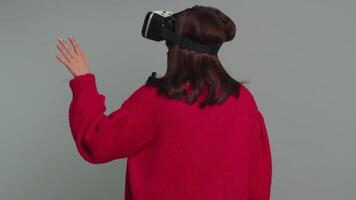 Young woman using virtual reality headset helmet to play simulation game app, watching content video