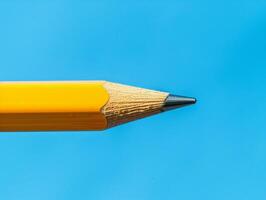 Close up of a sharp yellow pencil tip against a vibrant blue background photo