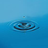 Perfect water droplet creating ripples on serene blue surface photo