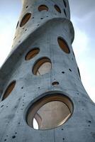 Modern concrete tower with circular windows under a cloudy sky photo