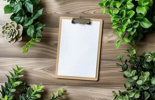 Blank clipboard on a wooden desk surrounded by green plants photo