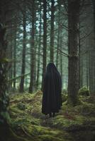 Mysterious figure in a dark cloak standing in a foggy forest photo