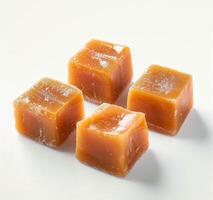 Glistening caramel cubes on a white background photo