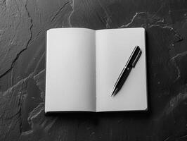 Open blank notebook with pen on a dark textured background photo