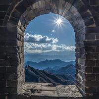 Sunburst over mountain range viewed through ancient stone archway photo