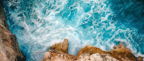 Aerial View of Turquoise Waves Crashing Against Rocky Cliffs photo