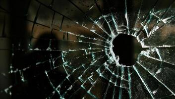 Close up of a shattered glass window with a hole in the center photo