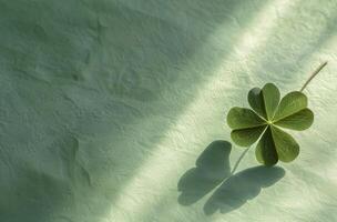 Four leaf clover casting a shadow on a textured green surface photo