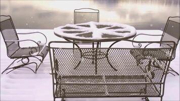 a table and chairs covered in snow by the lake video