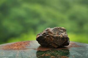 Rustic rock on a mossy surface with a blurred green background photo