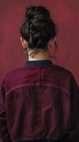 Young woman with an elegant bun hairstyle standing against a red textured background photo