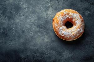 Freshly baked sugar dusted donut on a dark textured background photo