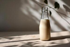 Glass bottle of milk with natural shadows from plant leaves photo