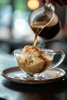 Pouring coffee over ice cream in a glass cup photo