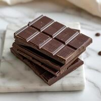 Stack of dark chocolate bars on a marble surface photo
