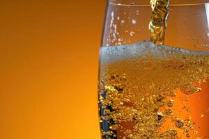 Close up of sparkling beverage being poured into a glass with a vibrant background photo