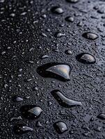 Raindrops on a dark surface with reflections photo